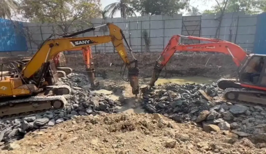 Excavation work in India with excavator machines breaking rock for foundation construction